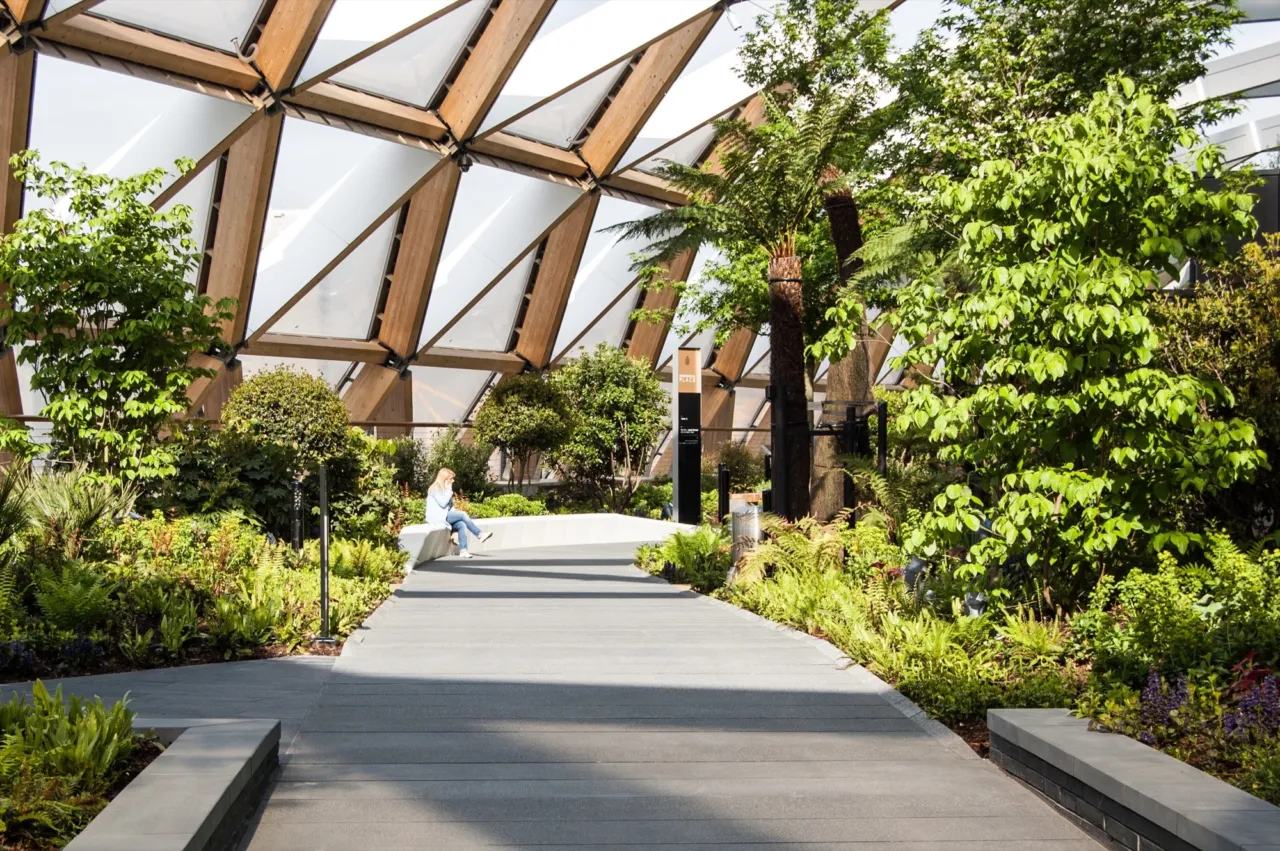 Woman enjoys the rare plants inside Crossrail Place Roof Garden, a roof garden above Canary Wharf Crossrail Station