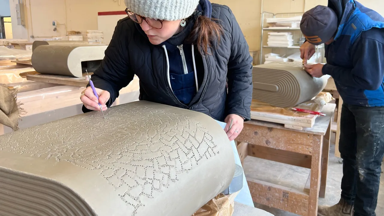 a person inscribing patterns on clay