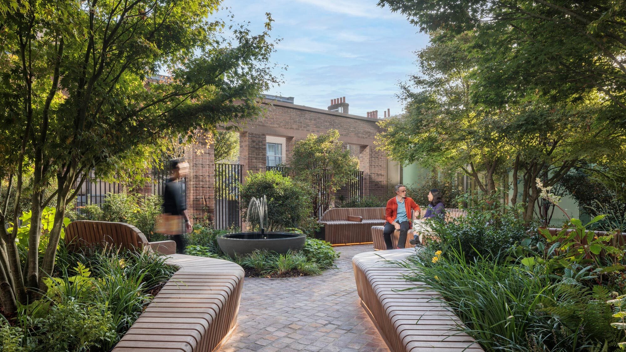 Shaded courtyard garden at 11 Belgrave Road with curved seating, lush planting, and sustainable landscape architecture design.