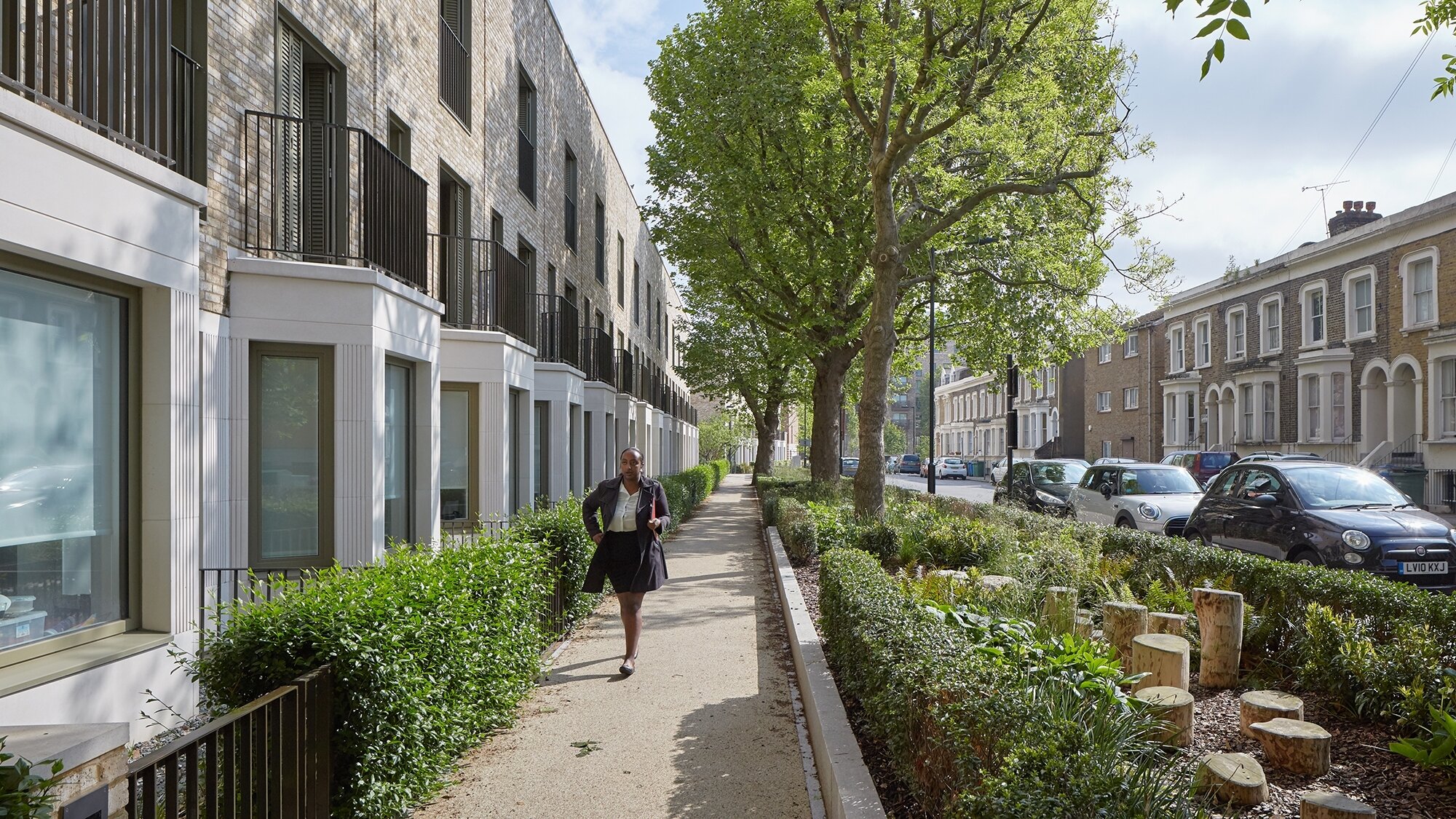 Tree lined residential street at South Gardens, Elephant Park, with generous planting, rain garden beds and widened pavements creating a greener public realm.