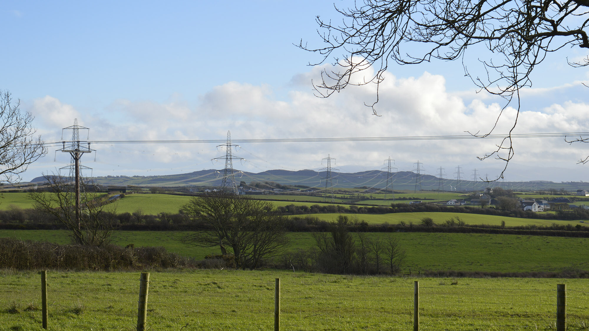 North Wales rural landscape with electricity pylons, farmland, and rolling hills showcasing energy infrastructure within natural countryside.
