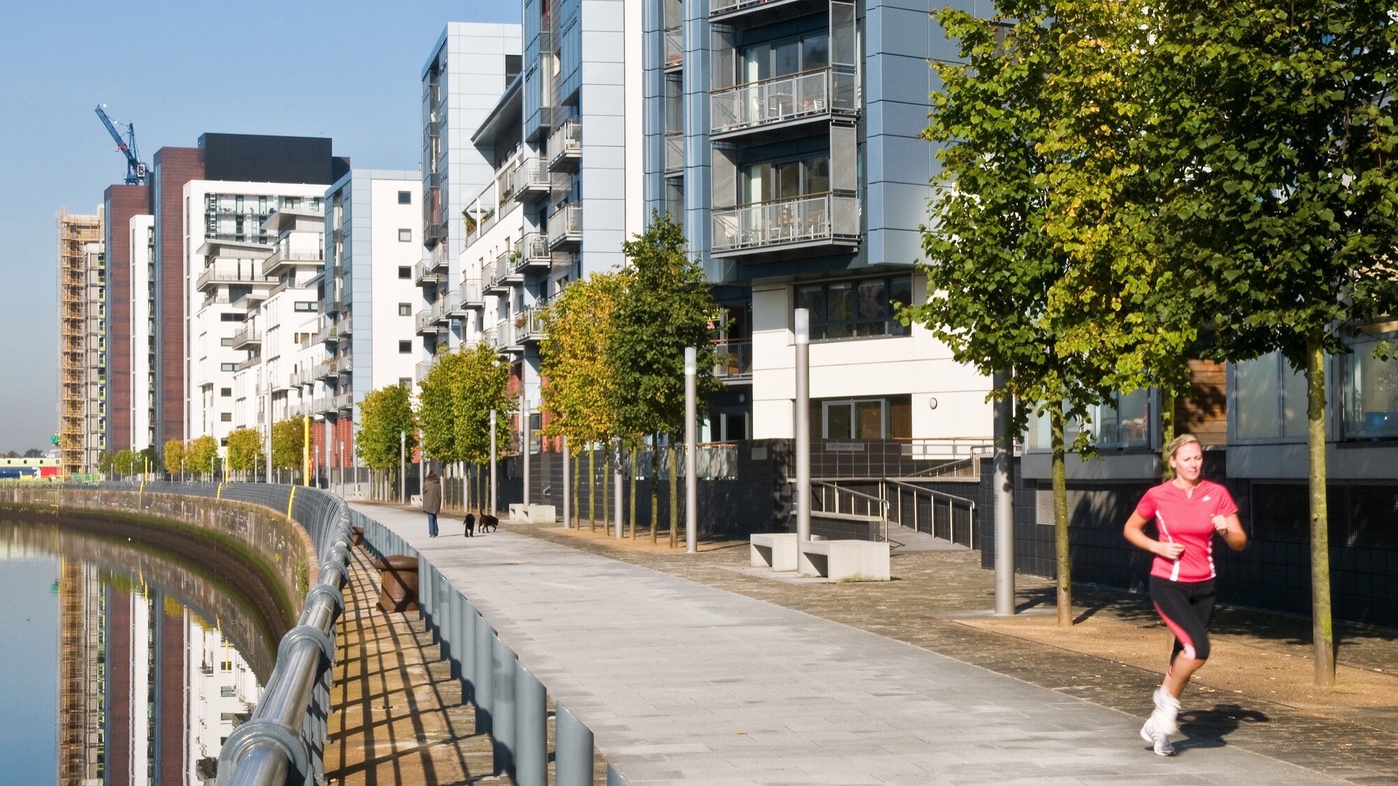 Riverside promenade with modern apartments, trees at Glasgow Harbour urban landscape regeneration project