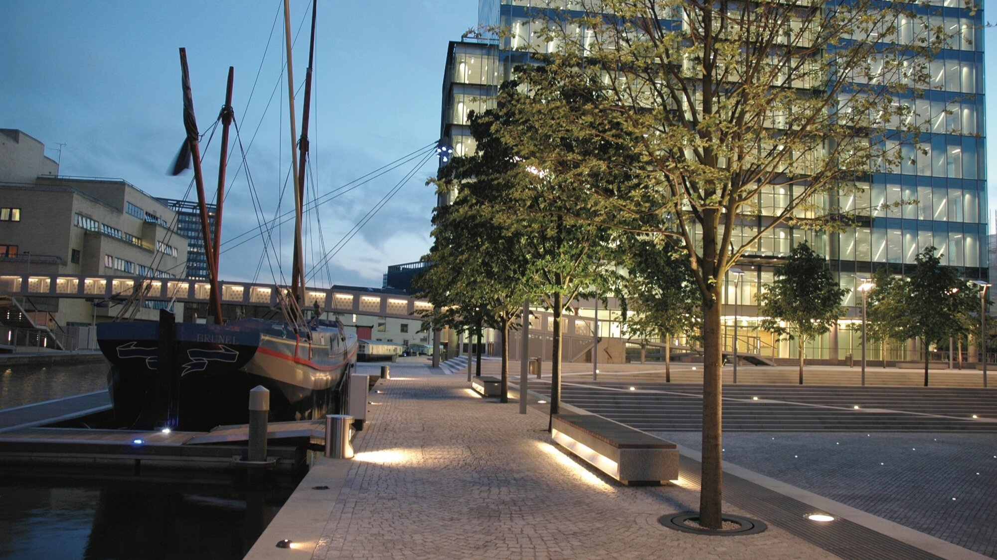 Contemporary landscape architecture at Paddington Basin featuring waterside promenade, plaza lighting, urban trees, and modern public realm design.