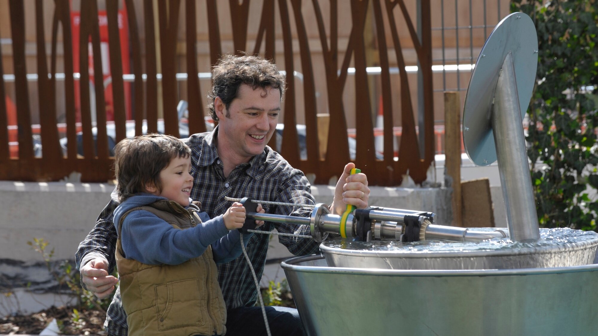 Interactive water play feature at Thinktank Science Garden with child and parent engaging in educational landscape design.