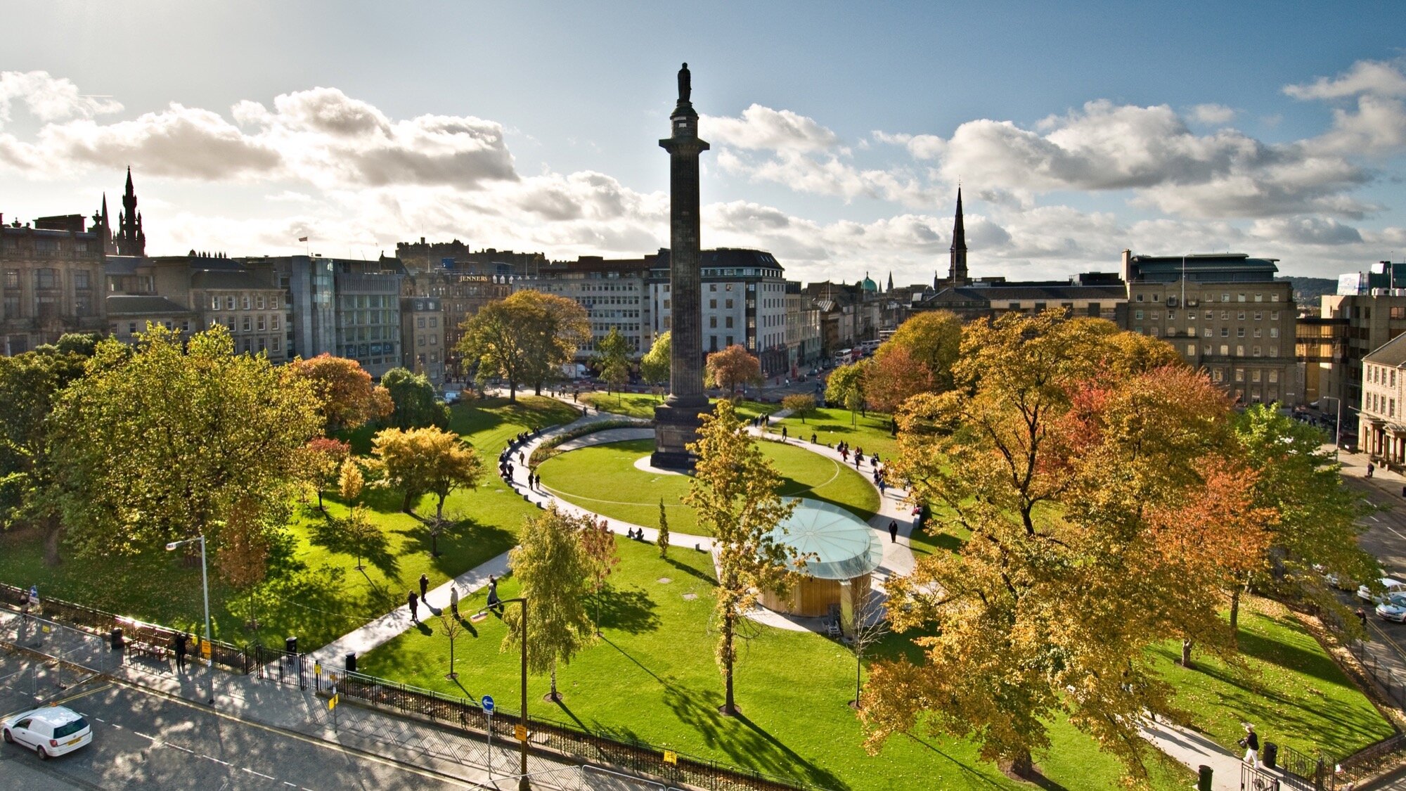 Aerial view of St Andrew Square in Edinburgh featuring formal lawn, curved paths, urban planting and water feature, all surrounding the central historic Melville Monument.