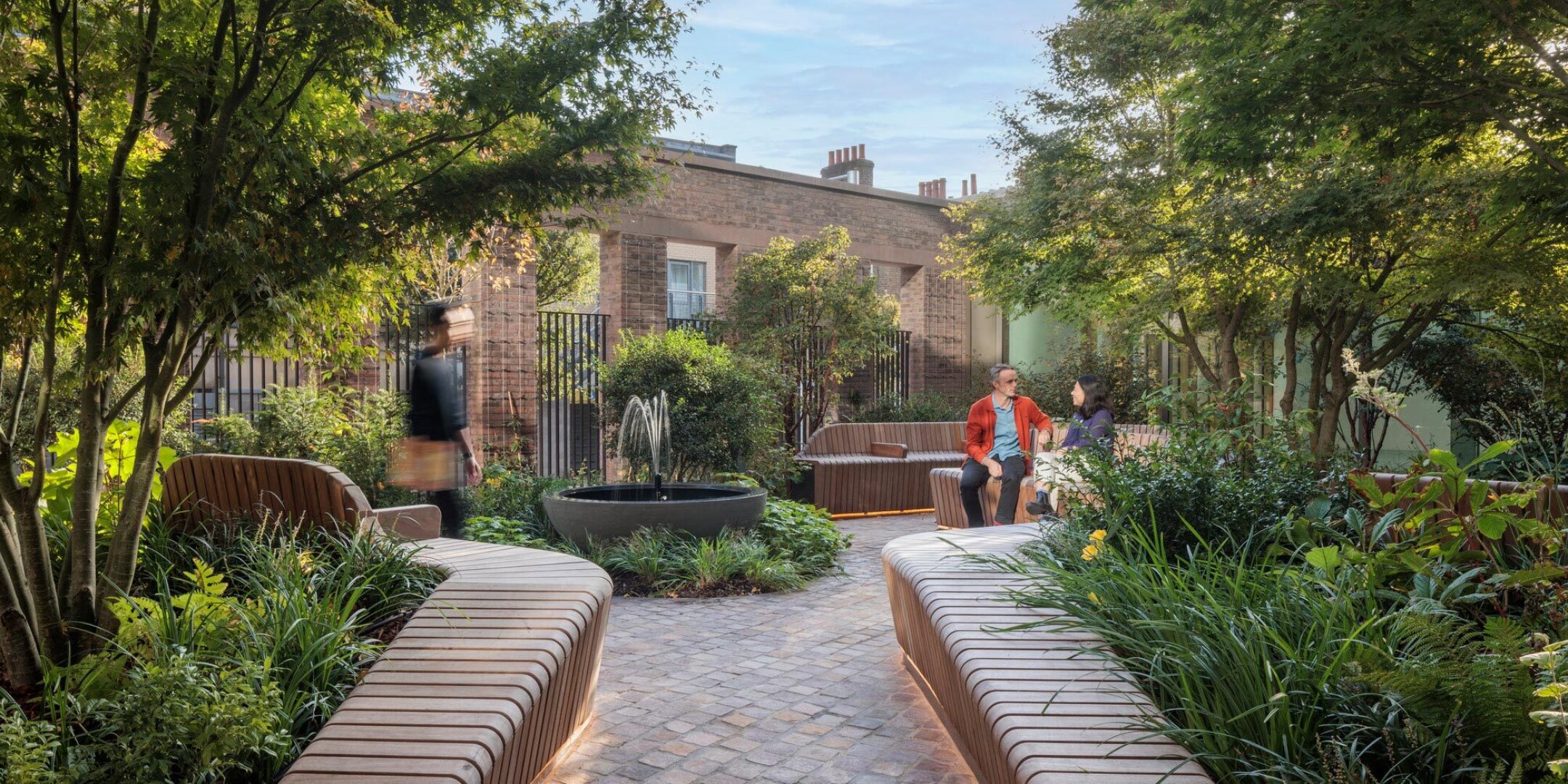 Shaded courtyard garden at 11 Belgrave Road with curved seating, lush planting, and sustainable landscape architecture design.
