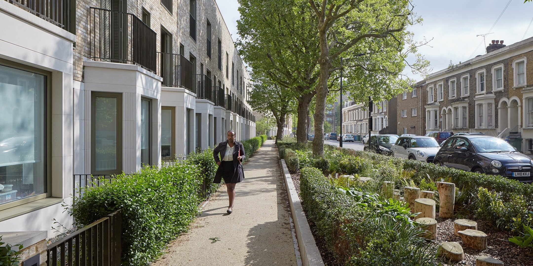 Tree lined residential street at South Gardens, Elephant Park, with generous planting, rain garden beds and widened pavements creating a greener public realm.