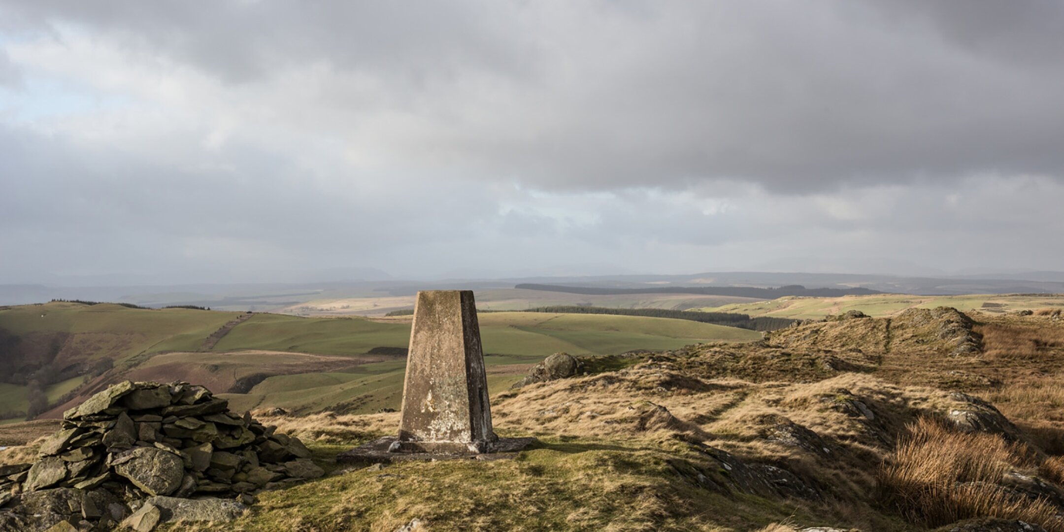 View across rolling upland landscape in Mid Wales with trig point and cairn, part of landscape planning for energy infrastructure studies.