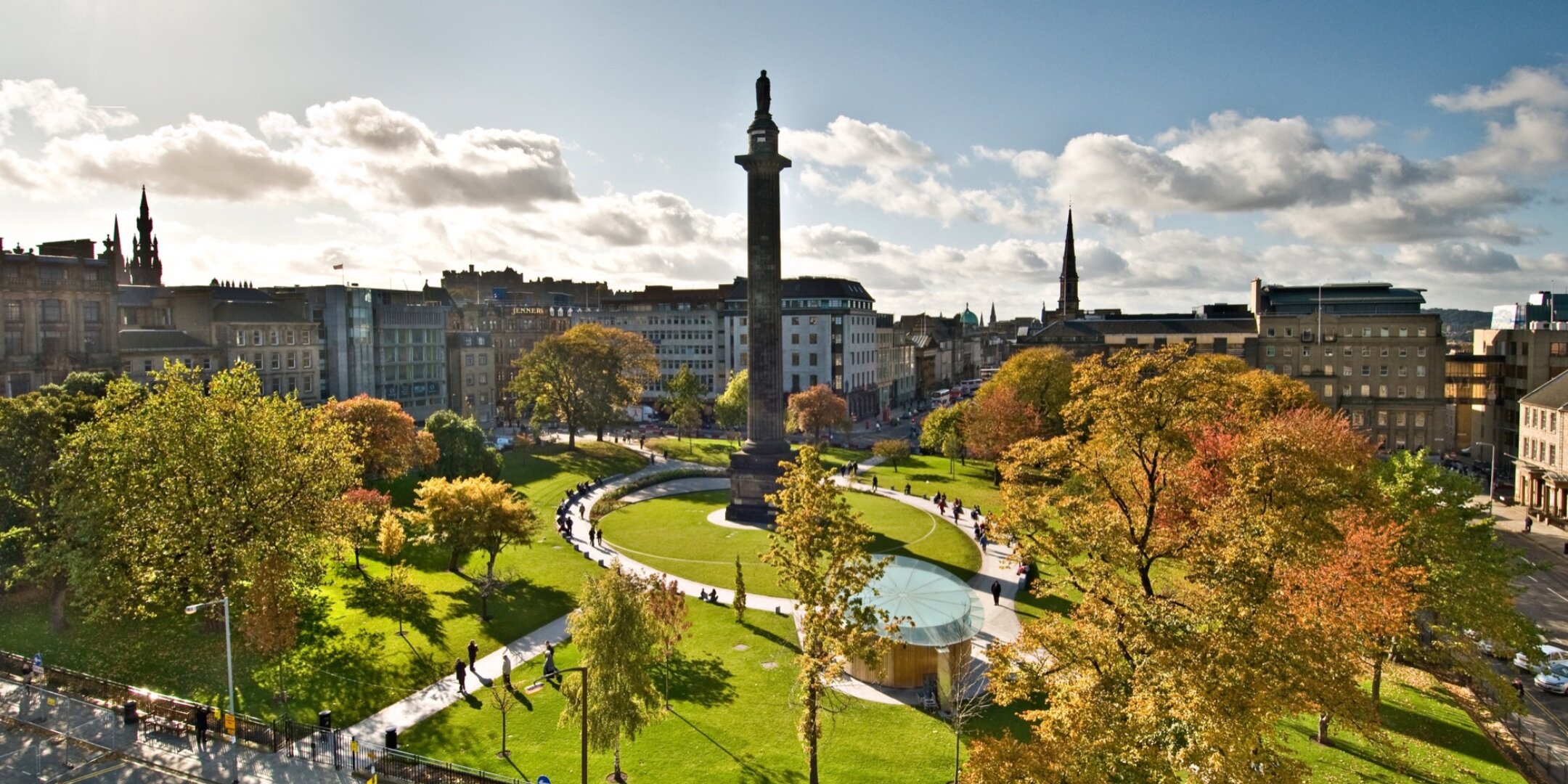 Aerial view of St Andrew Square in Edinburgh featuring formal lawn, curved paths, urban planting and water feature, all surrounding the central historic Melville Monument.