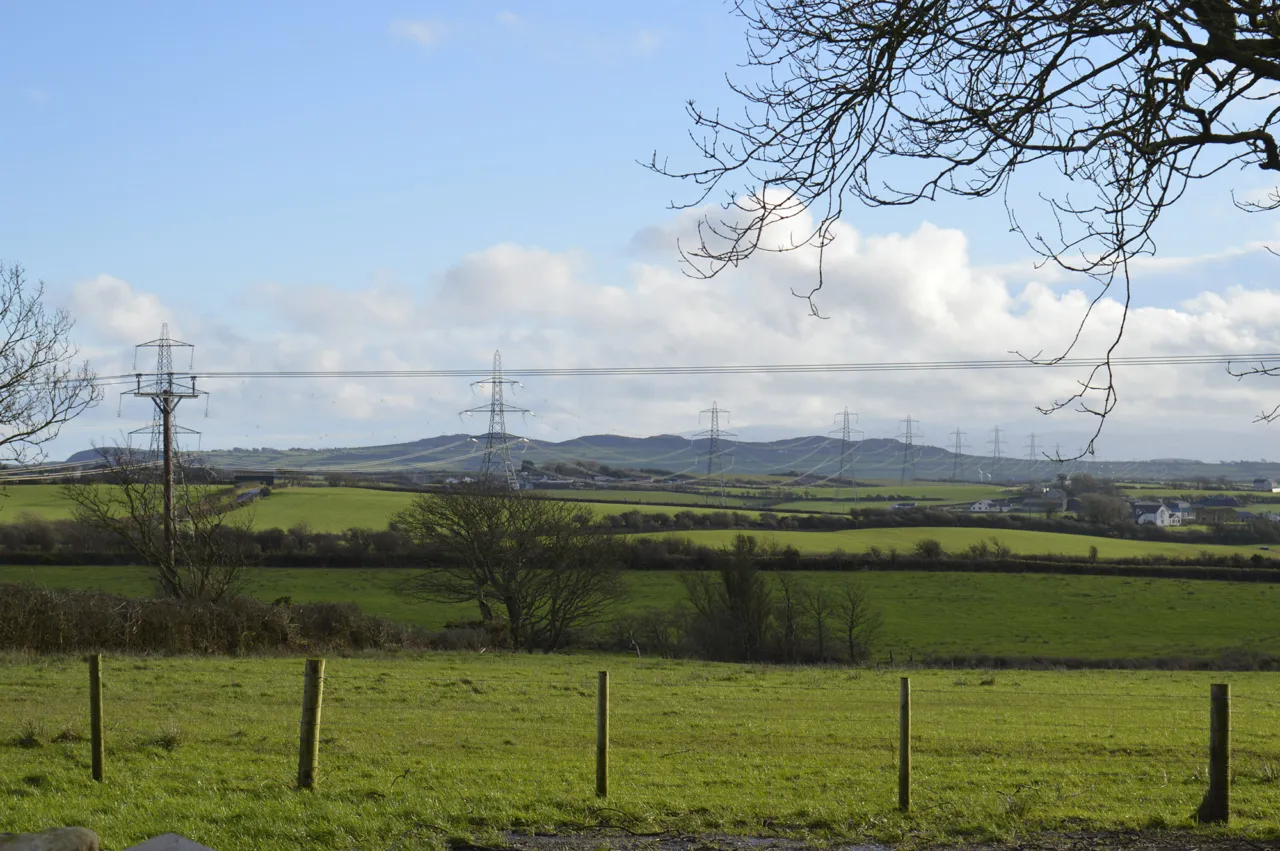 North Wales rural landscape with electricity pylons, farmland, and rolling hills showcasing energy infrastructure within natural countryside.