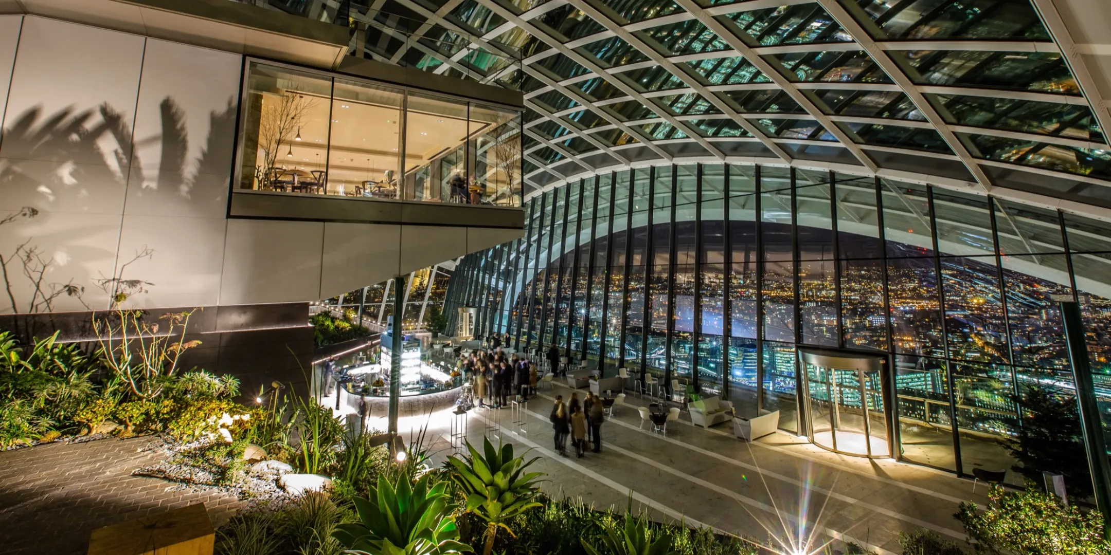Sky Garden at night with tropical planting, architectural lighting, and glazed roof showcasing elevated indoor landscape design by London based practice, Gillespies.