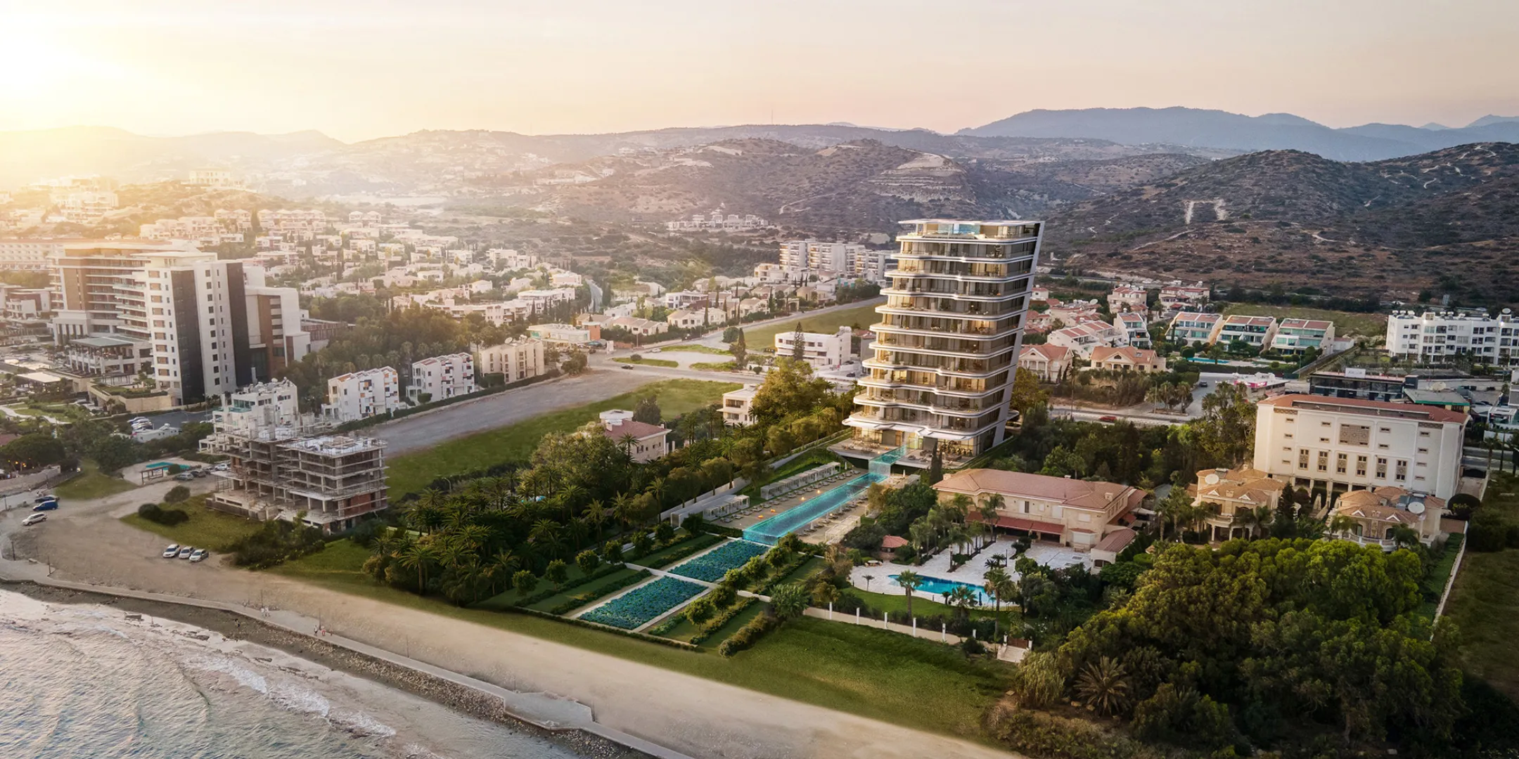 A landmark residential tower rising above formal waterfront gardens, set between the coastline and the hills of Limassol.
