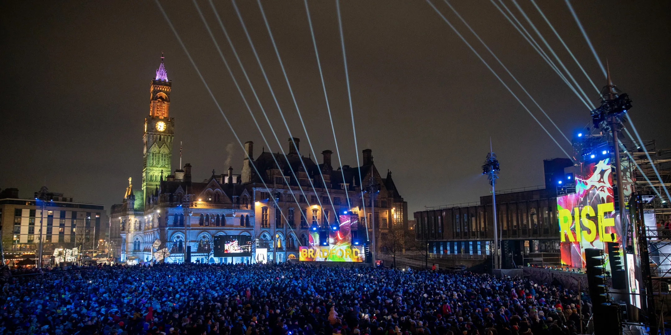 Bradford Rise Event as part of the launch of Bradford City of Culture. Night event at Bradford City Park with lighting design and crowd, showcasing flexible public space and urban landscape architecture by Gillespies.