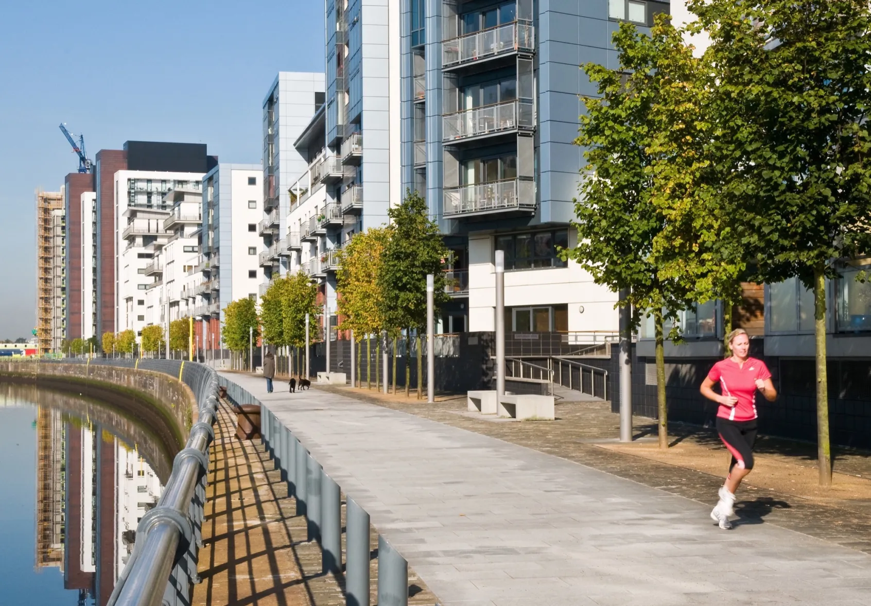 Riverside promenade with modern apartments, trees at Glasgow Harbour urban landscape regeneration project