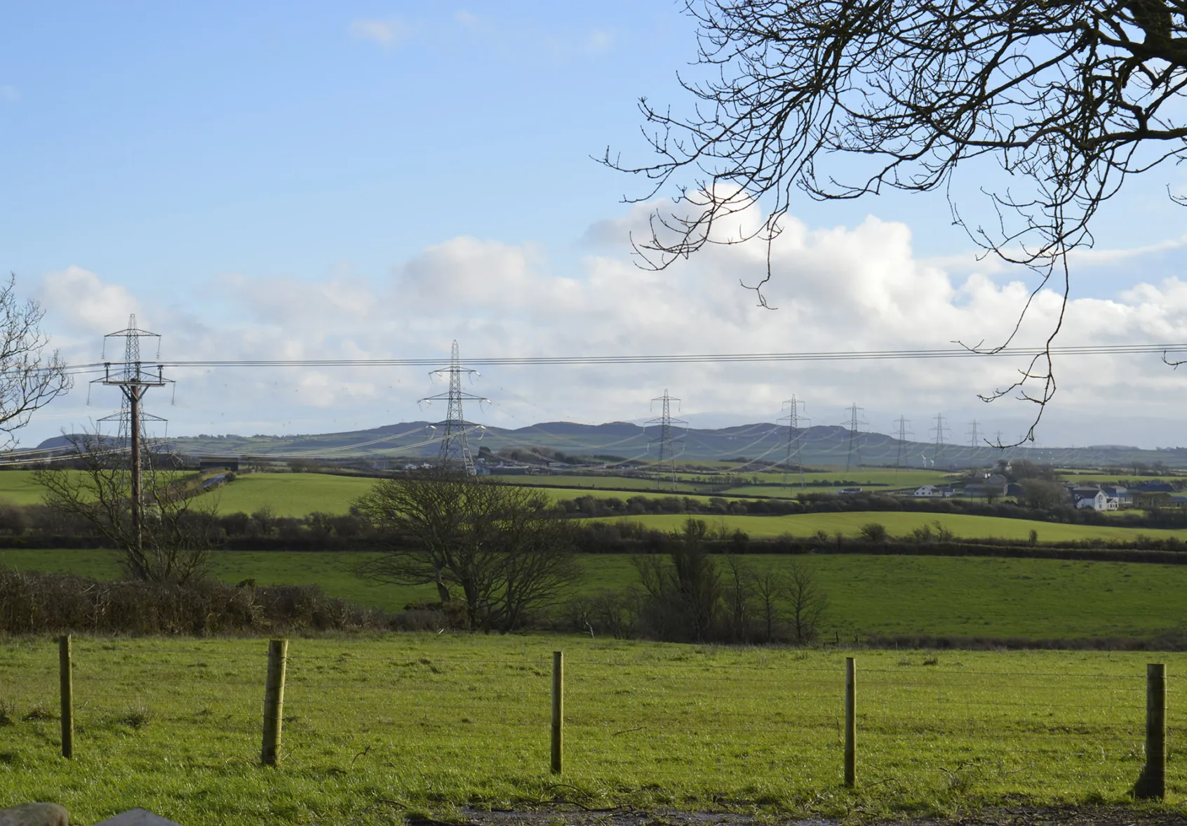 North Wales rural landscape with electricity pylons, farmland, and rolling hills showcasing energy infrastructure within natural countryside.
