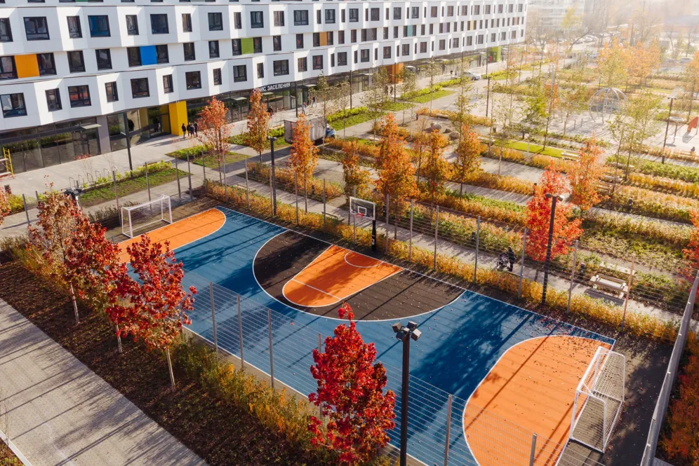 Colorful sports court at PIK Green Park Moscow surrounded by autumn trees and modern sustainable landscape architecture design.