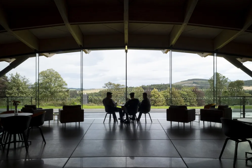 Interior of Macallan Distillery with panoramic glass views of landscaped Scottish countryside and sustainable architecture.