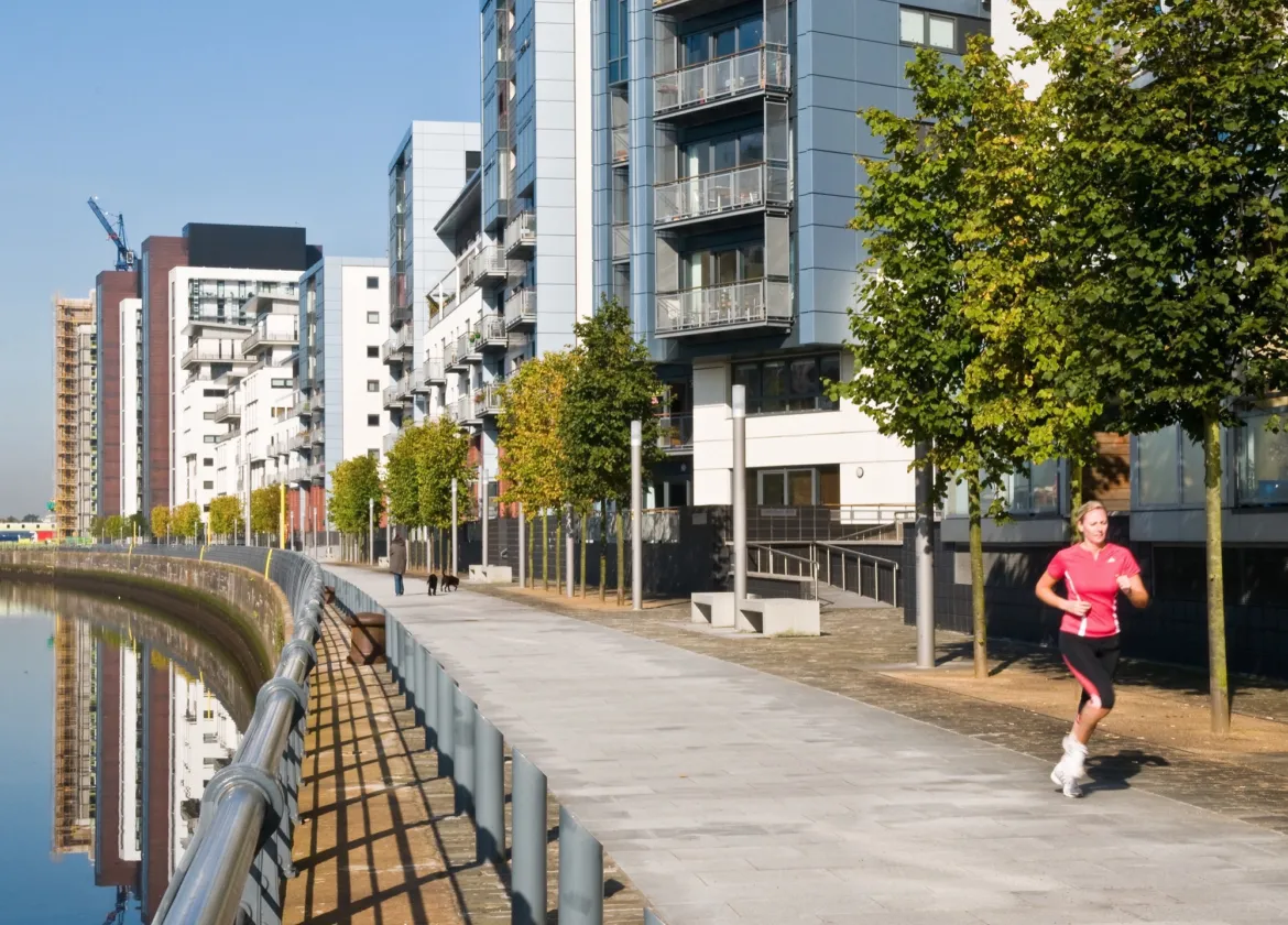 Riverside promenade with modern apartments, trees at Glasgow Harbour urban landscape regeneration project