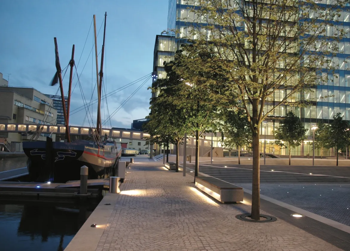 Contemporary landscape architecture at Paddington Basin featuring waterside promenade, plaza lighting, urban trees, and modern public realm design.