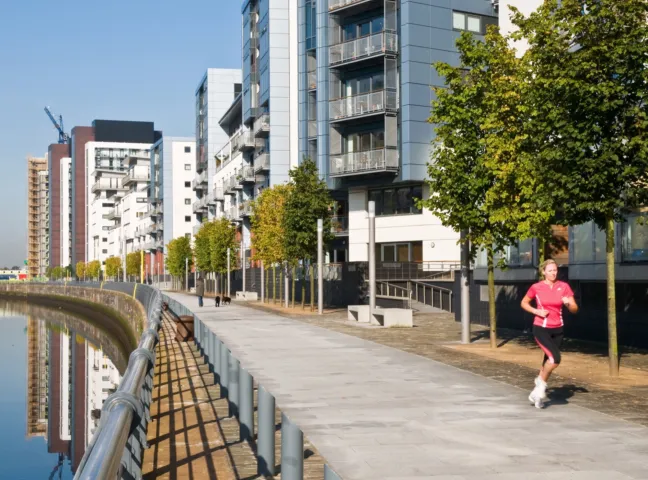 Riverside promenade with modern apartments, trees at Glasgow Harbour urban landscape regeneration project