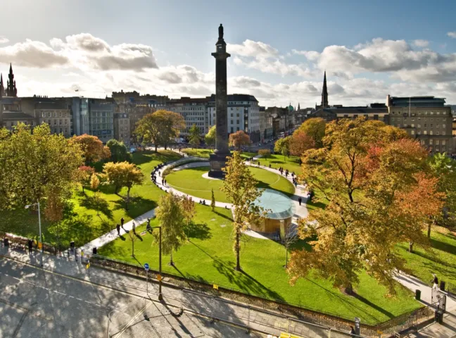 Aerial view of St Andrew Square in Edinburgh featuring formal lawn, curved paths, urban planting and water feature, all surrounding the central historic Melville Monument.