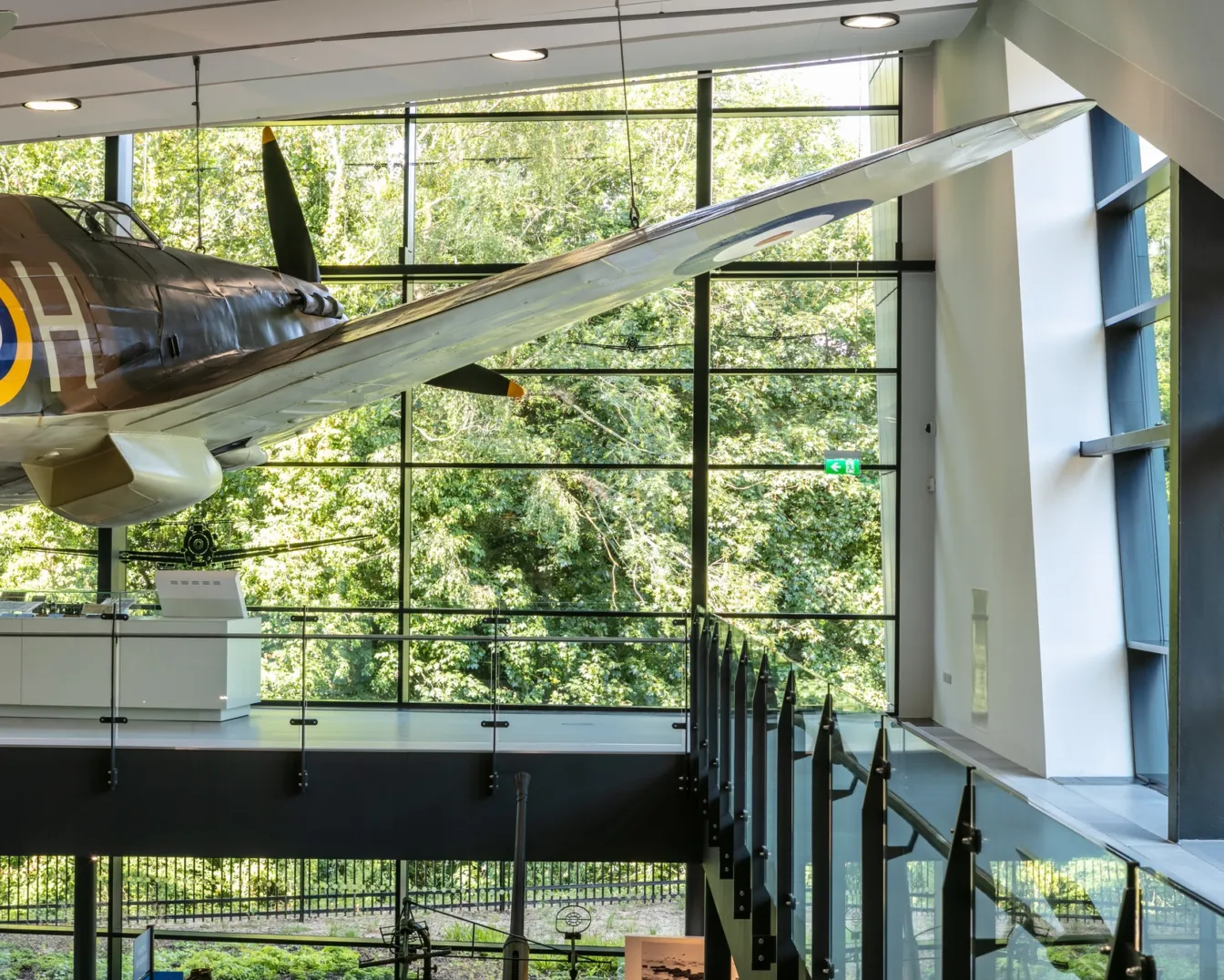 A suspended Spitfire takes centre stage within the exhibition hall, set against panoramic views of the surrounding woodland