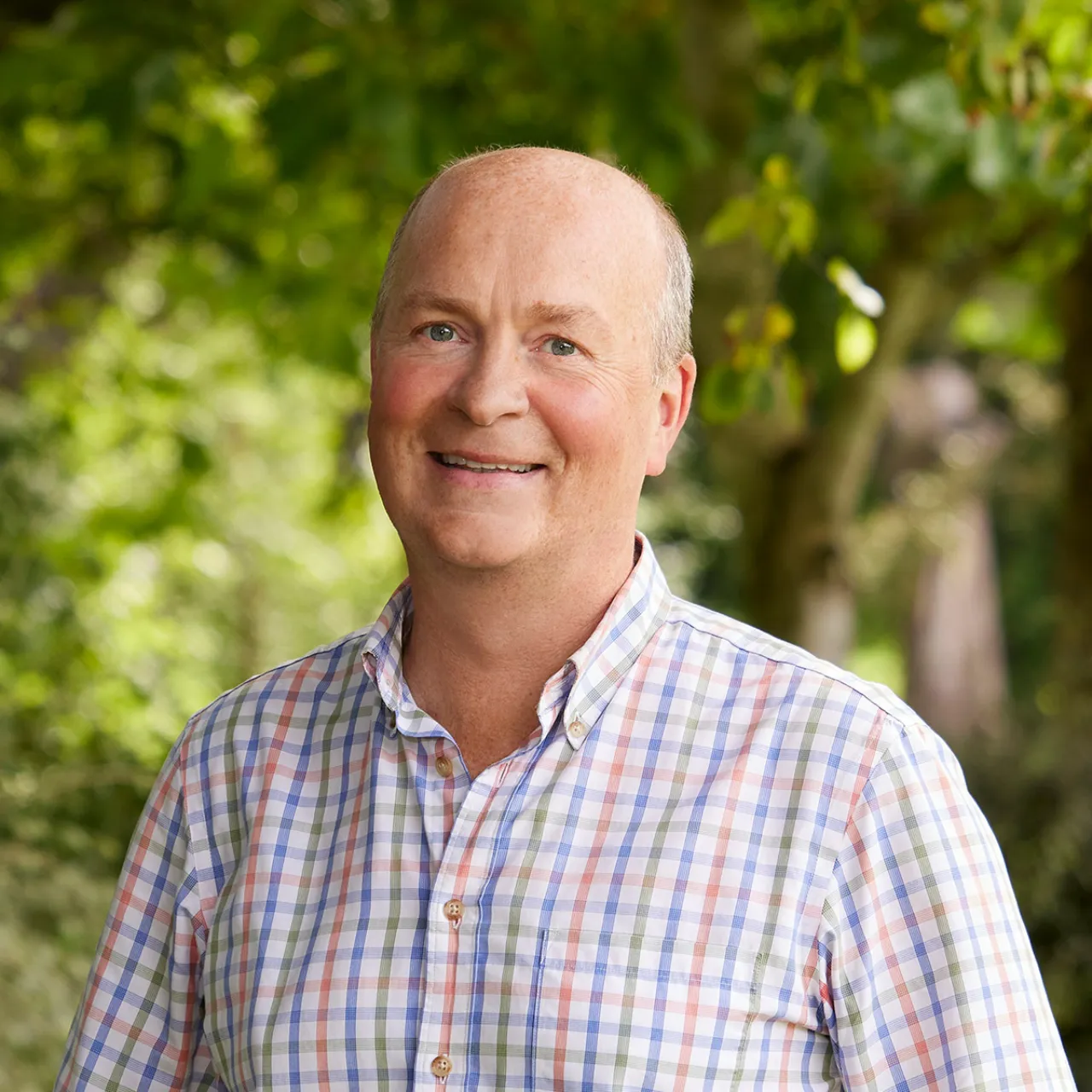Warren Chapman, Chartered Landscape Architect and Associate Partner at Gillespies, smiling outdoors in a Manchester parkland setting.
