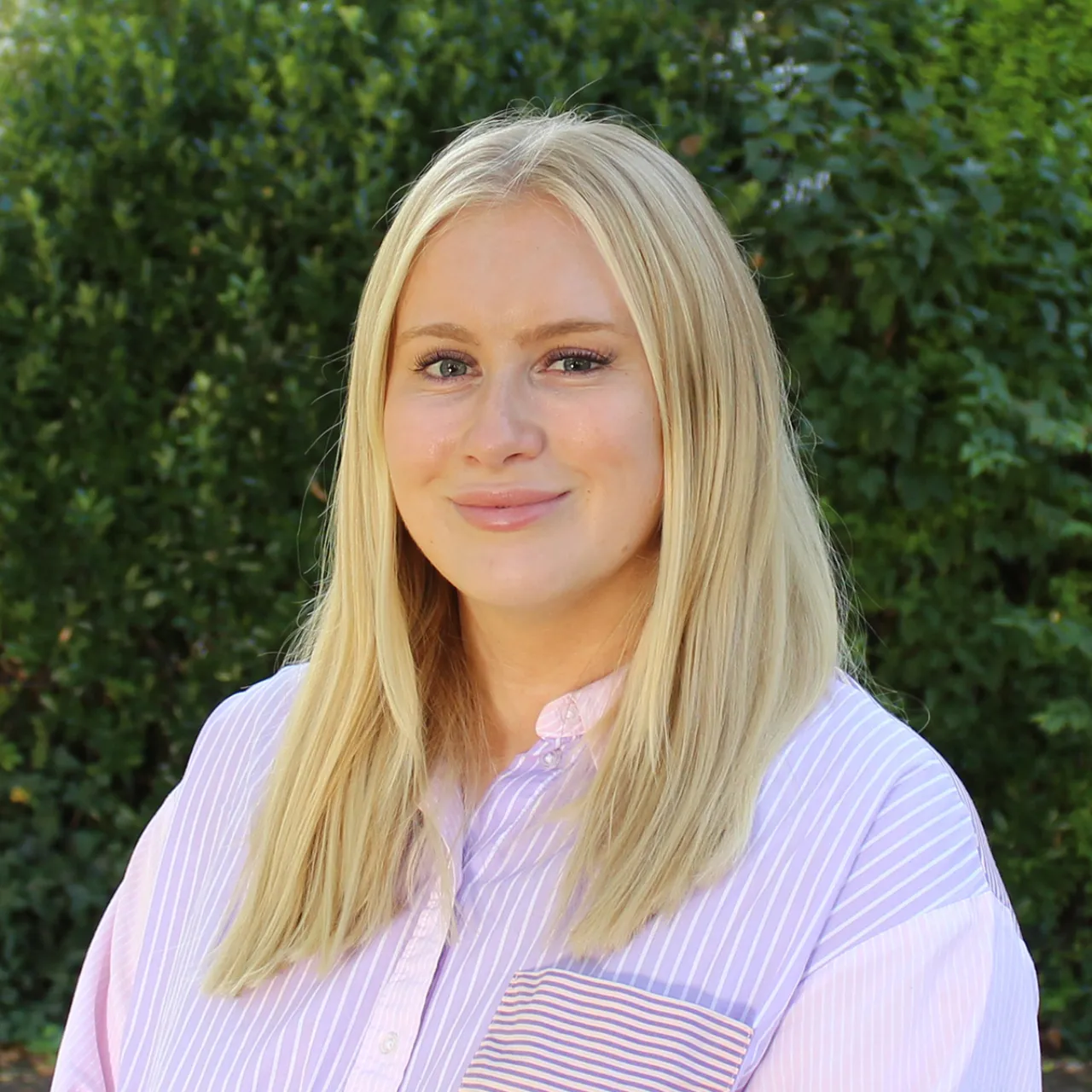 Hannah Butler, Executive Assistant for Partners in London, standing in front of a greenwall