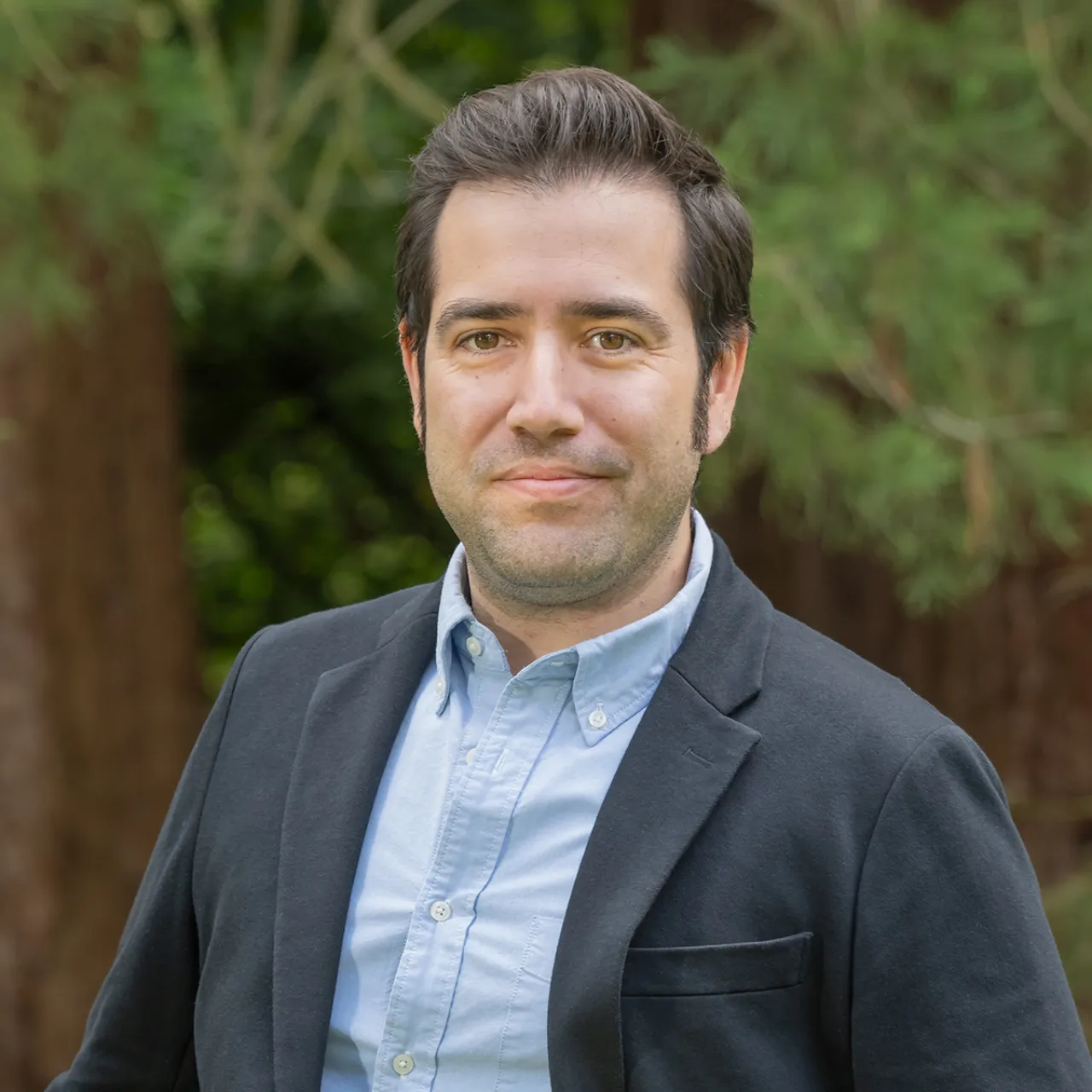 Alp Adal, Chartered Landscape Architect and Associate at Gillespies' Oxford studio, standing in a woodland setting