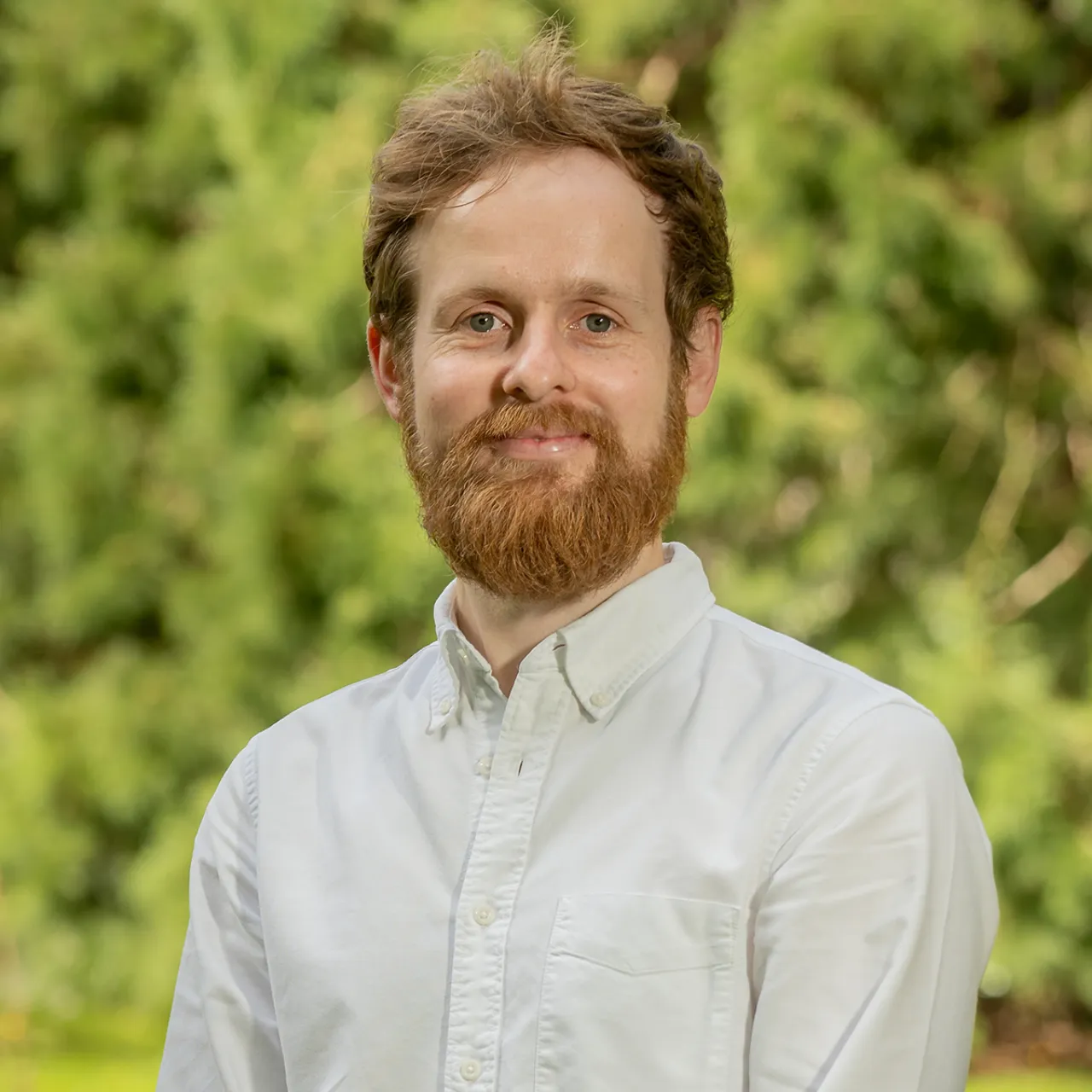 Kyle Mackintosh, Senior Landscape Architect at Gillespies’ Oxford studio, looking at the camera in an outdoor leafy setting.