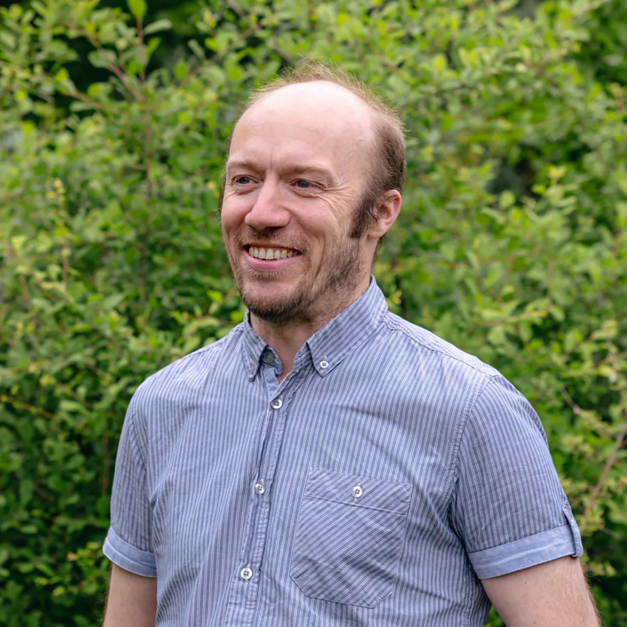 Mathew Conn, Principal Architectural Technologist based in Gillespies’ Leeds studio, gazing away from the camera in a green setting