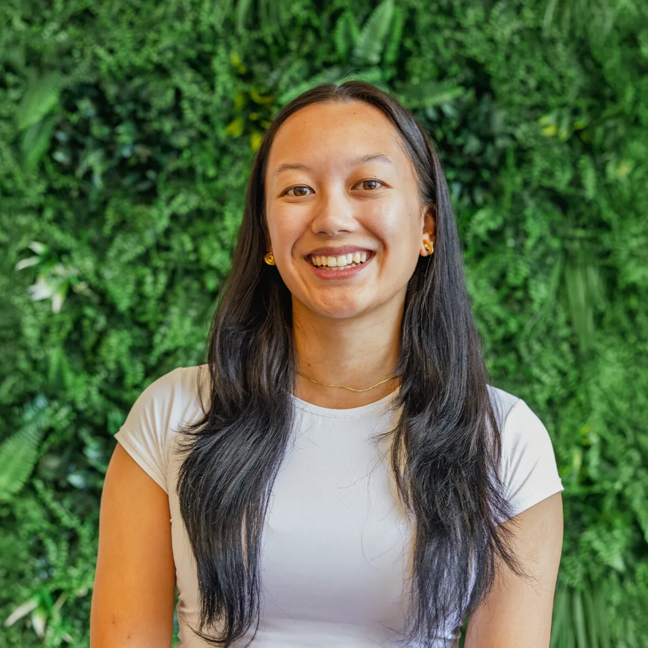 Graduate Landscape Architect Angeline Aspacio smiling in front of a green wall in Manchester