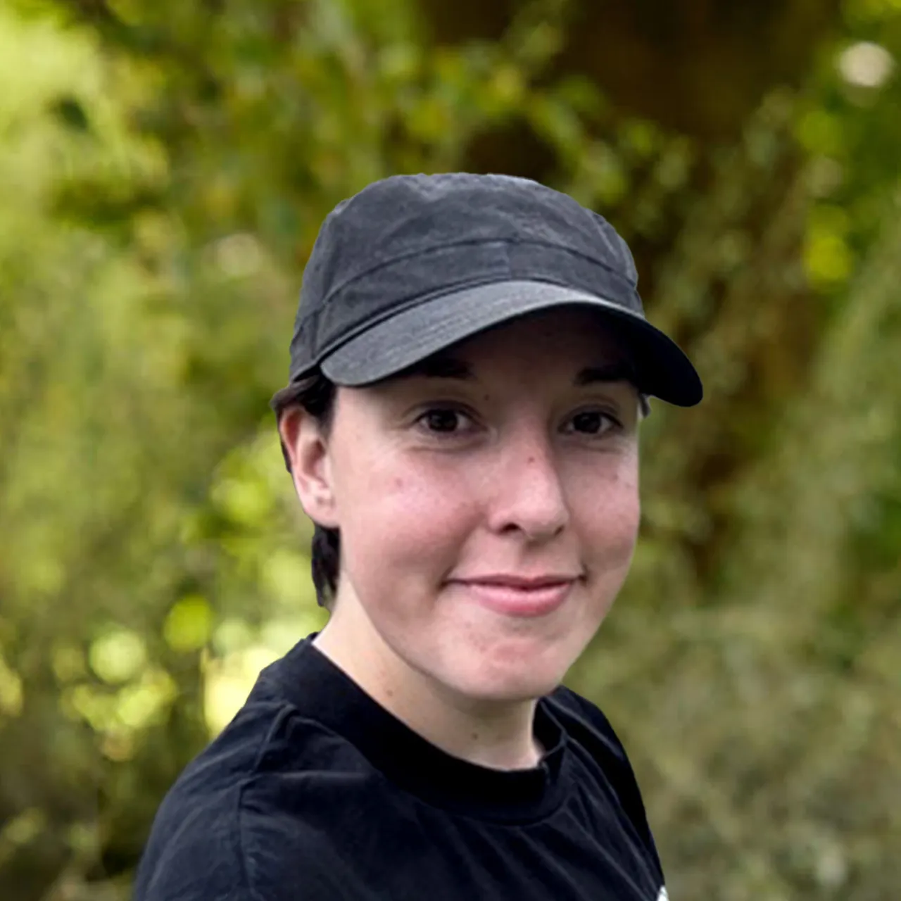 Architect Amy Featherstone smiling in front of a green background with a hat on