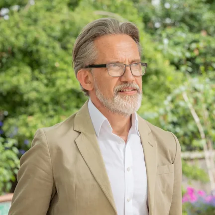 Stephen Richards, a Partner at Gillespies and biophilic design specialist, standing in a green park in London.