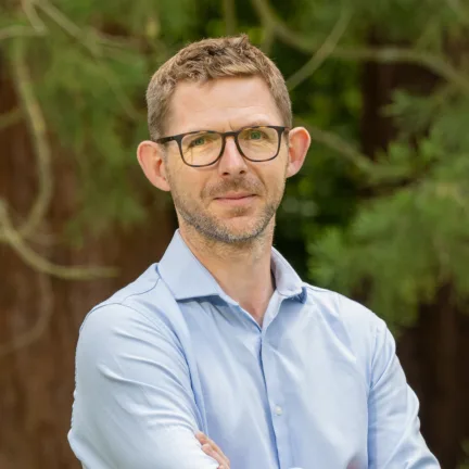 Oliver Smith, Partner at Gillespies' Oxford studio, smiling in a woodland setting